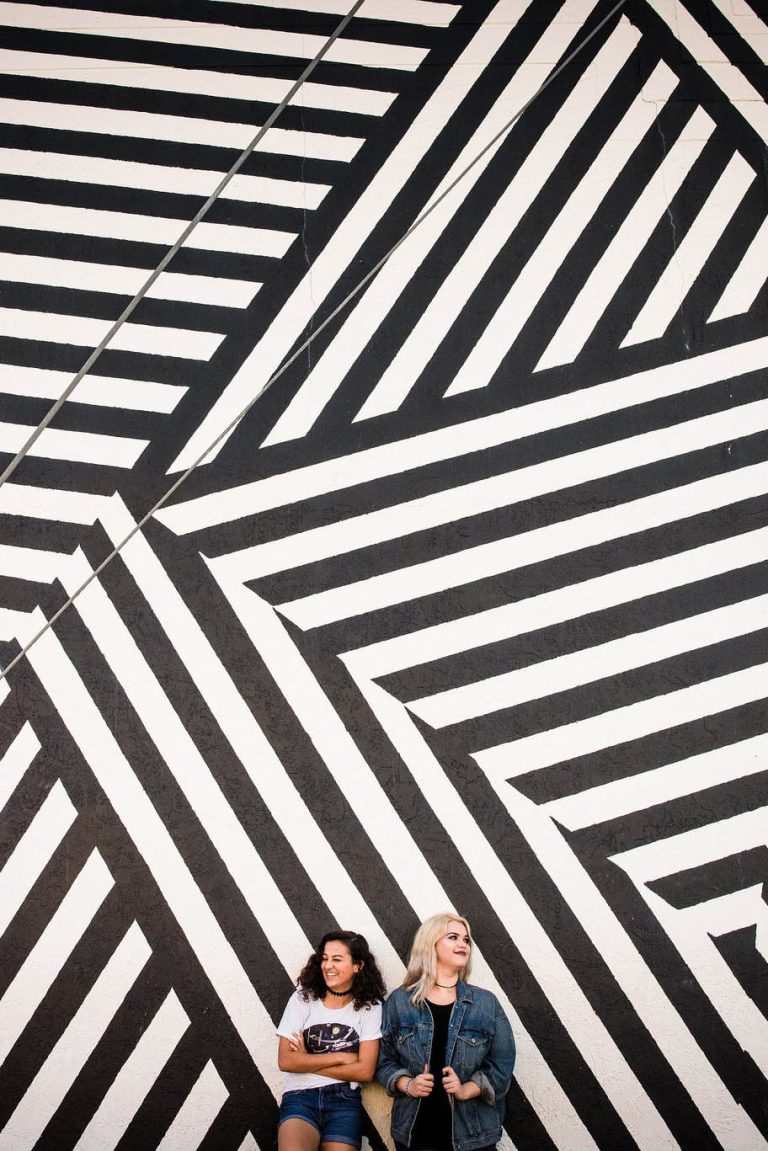 Fun portrait of two young women standing against a black and white striped wall - photography by Florida portrait photographer Zee Anna Photography